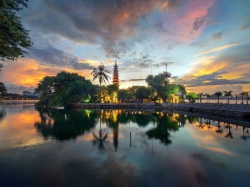 Tran Quoc Pagoda reflected on Hanoi's West Lake at sunset, a highlight of this Vietnam 10 day tour