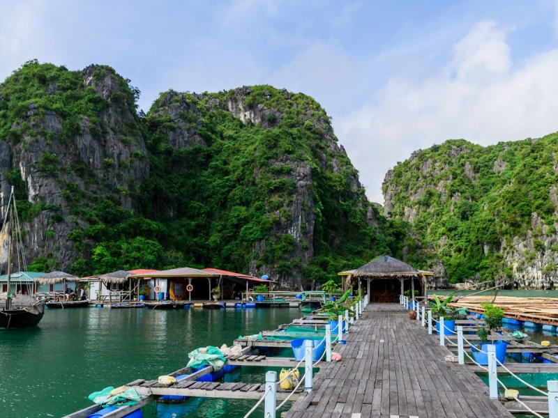 A Guide to Visiting Halong Bay for the First Time Floating village houses beneath karst cliffs in Ha Long Bay