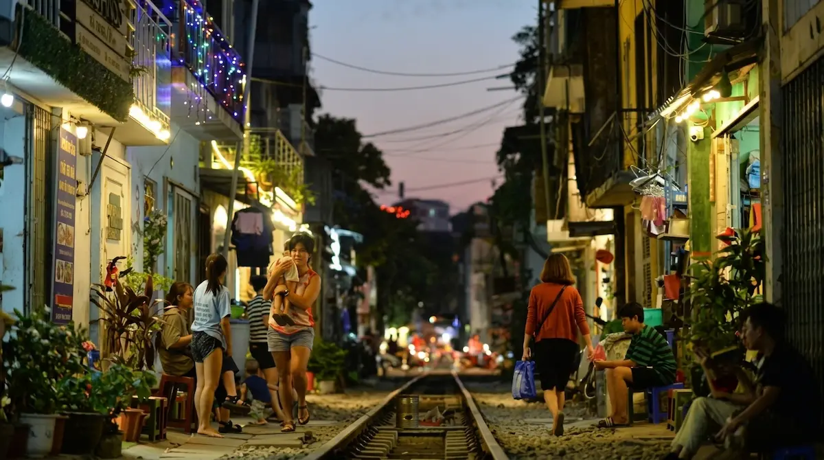 Local residents walking and gathering along Hanoi Train Street at twilight 