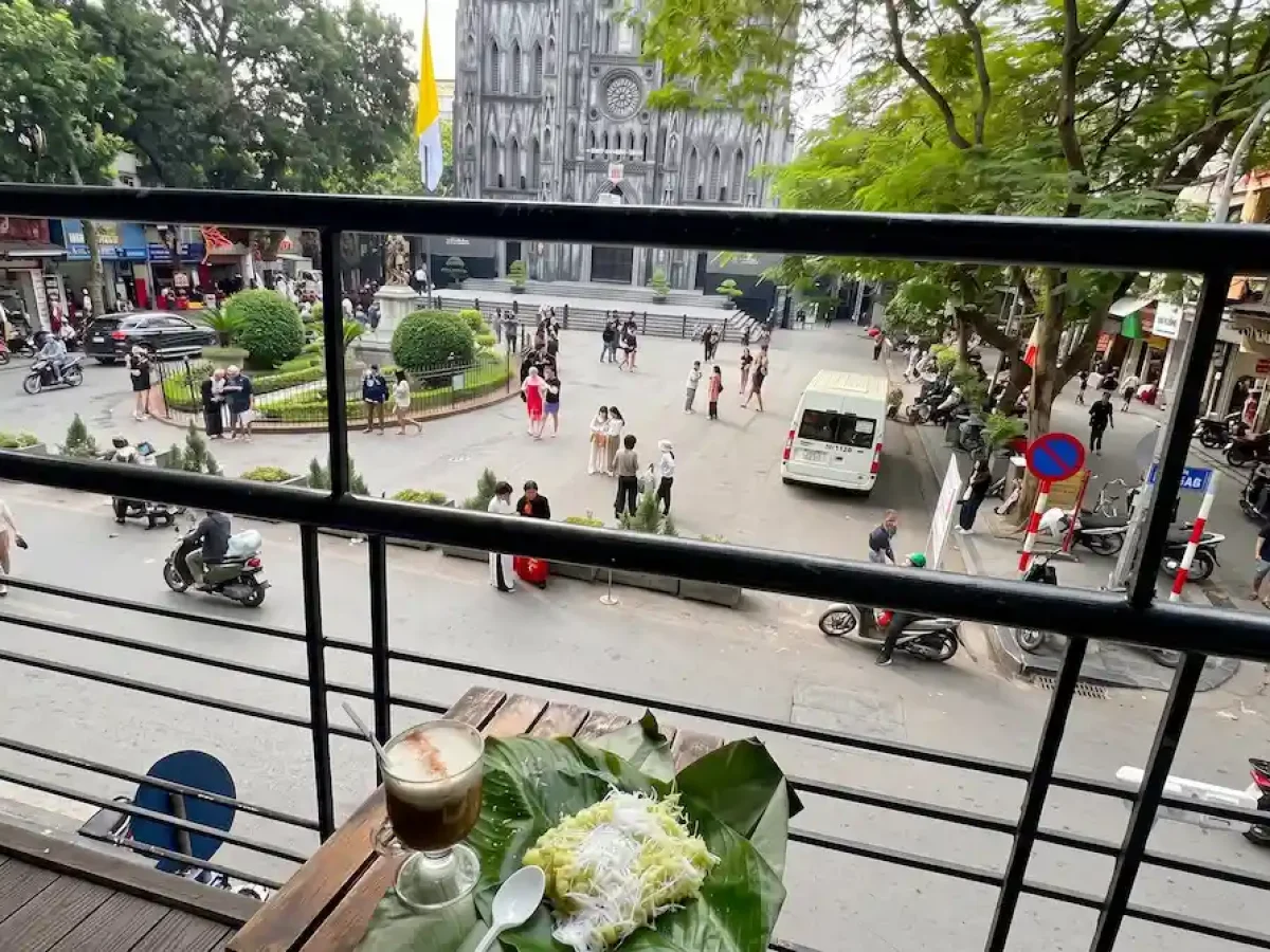 Best Balcony Coffee View Near St. Joseph's Cathedral Hanoi - Vietnam Discovery Tours Balcony view of St. Joseph's Cathedral Hanoi with iced coffee and green sticky rice snack - Vietnam Discovery Tours