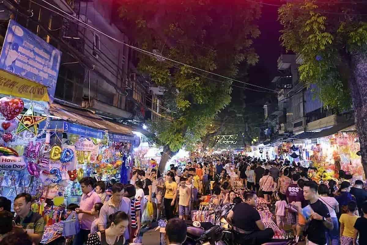 Hang Ma Street Night Market Mid-Autumn Festival Experience — Vietnam Discovery Tours Crowds of locals and tourists exploring vibrant, brightly lit toy stalls on Hang Ma Street during the Mid-Autumn Festival in Hanoi Old Quarter.