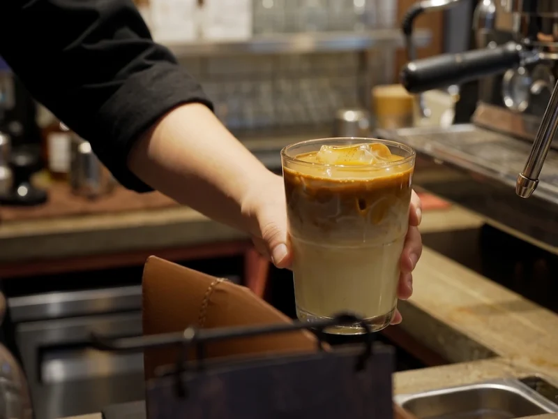 Specialty Iced Latte at Infusion Cafe Au Trieu - Vietnam Discovery Tours Barista serving a layered specialty iced latte over ice at Infusion Cafe near St. Joseph's Cathedral Hanoi