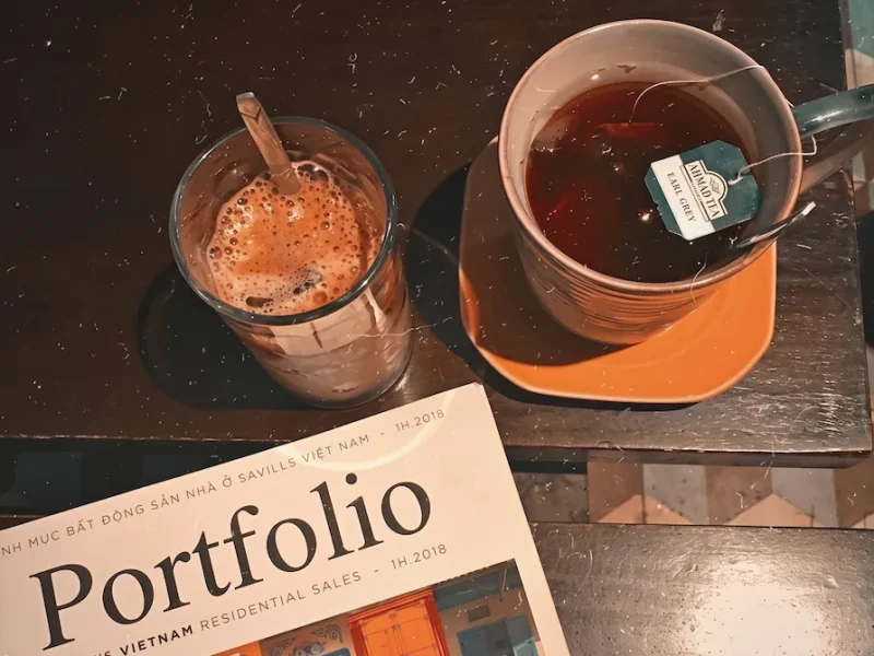 Cozy Coffee and Tea Table at Hanoi House Cafe - Vietnam Discovery Tours Iced coffee with cinnamon stick and hot tea on a rustic wooden table at Hanoi House Cafe near St. Joseph's Cathedral Hanoi