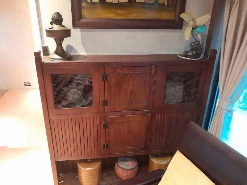  Vintage wooden cabinet with mesh doors and decor.