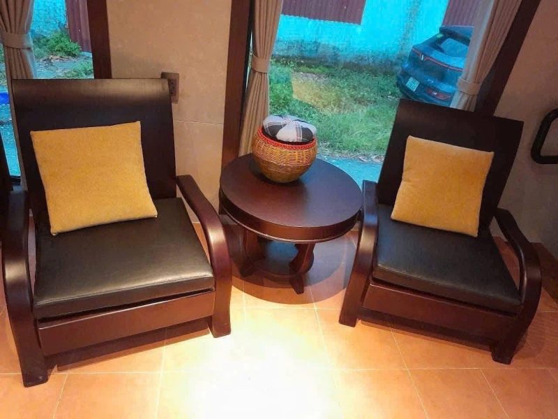 Cozy wooden chairs with cushions by the window.