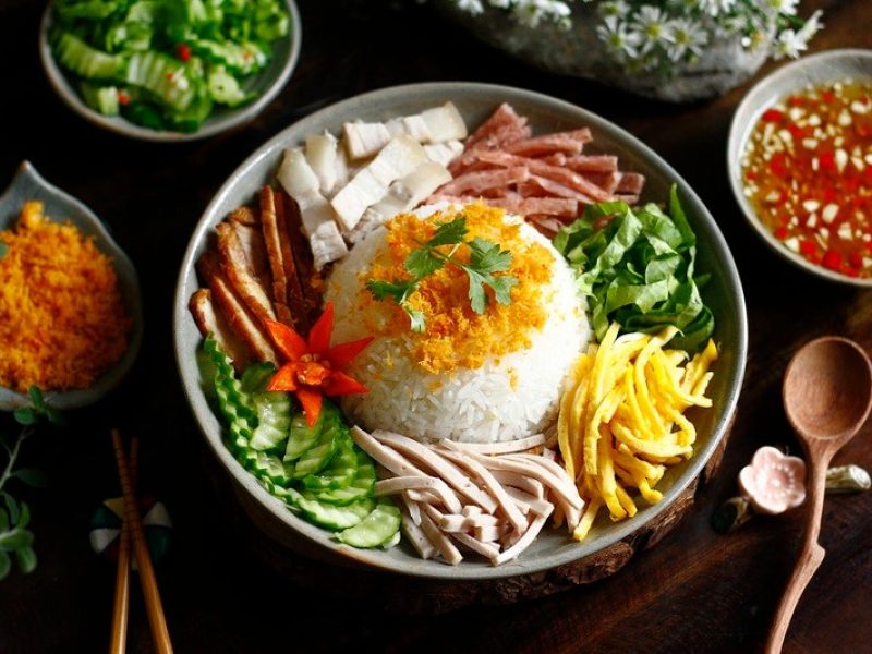 Colorful Hue-style dish with rice, shredded pork, sausage, herbs and vegetables