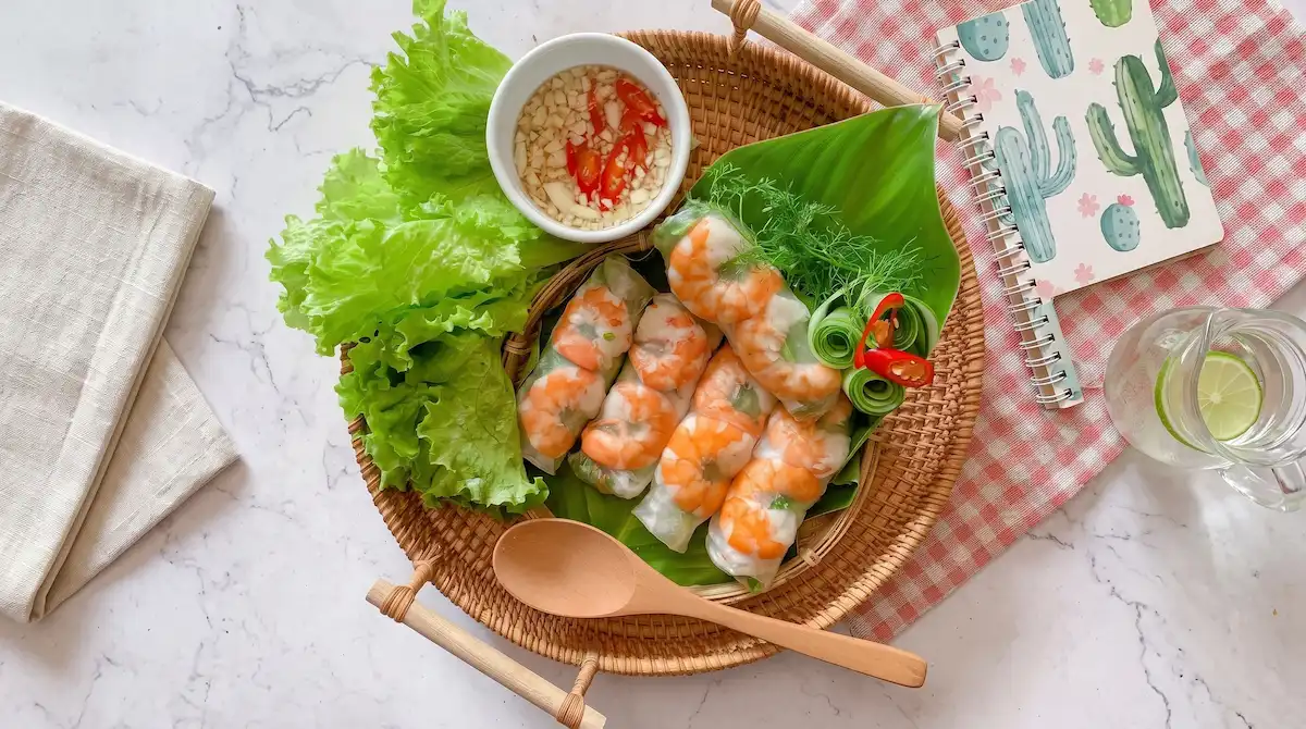 Experience authentic Vietnamese spring rolls (Gỏi Cuốn) wrapped with juicy prawns, fresh lettuce, and traditional herbs, served alongside authentic dipping sauce on culinary tours curated by Vietnam Discovery Tours. Authentic Vietnamese fresh spring rolls goi cuon with shrimp and dipping sauce by Vietnam Discovery Tours