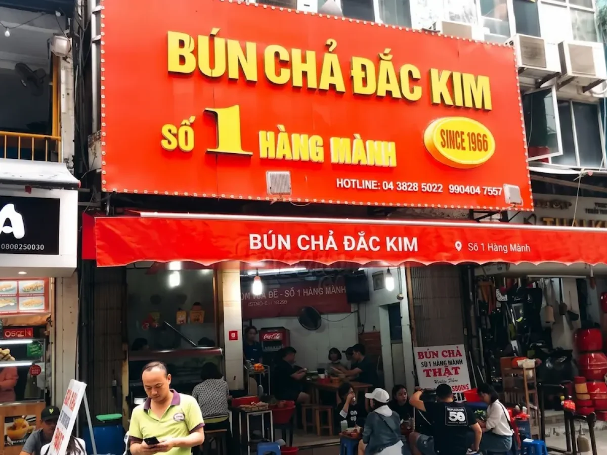 Bun Cha Dac Kim Storefront Hanoi - Vietnam Discovery Tours Storefront and iconic orange signboard of Bun Cha Dac Kim on Hang Manh Street Hanoi - Vietnam Discovery Tours