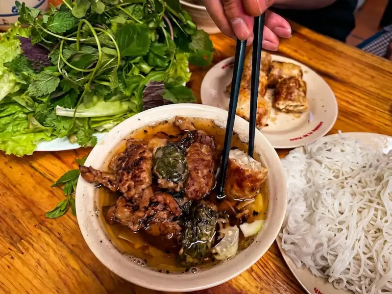 Bun Cha Sinh Tu Hanoi - Vietnam Discovery Tours Authentic Bun Cha Sinh Tu in Hanoi with grilled pork patties, fresh herbs, and rice noodles - Vietnam Discovery Tours