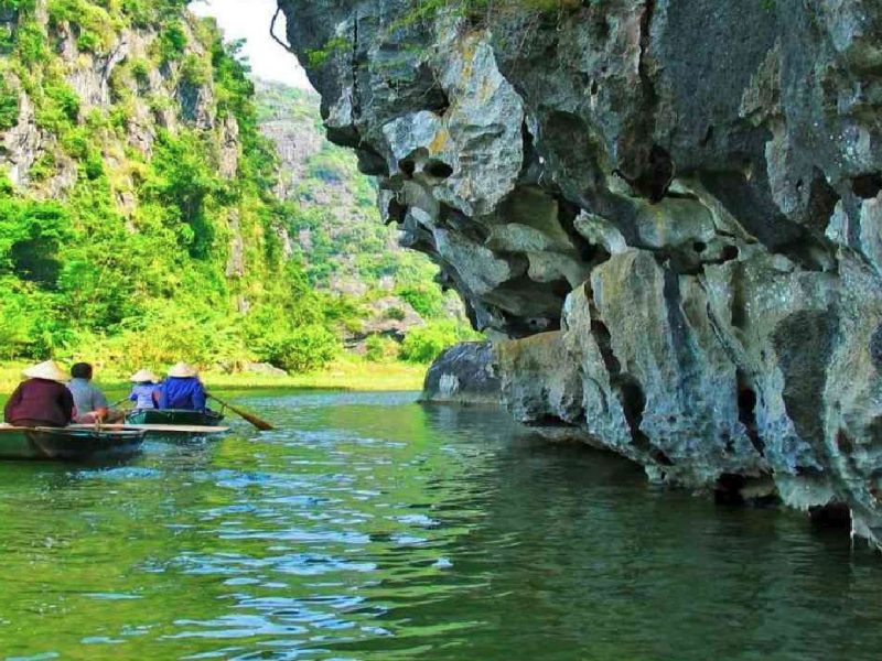 Tam Coc cave entrance Tourists in a rowboat approaching a cave entrance beneath towering limestone cliffs, Ninh Binh