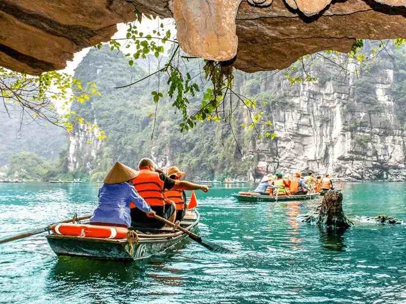 Tam Coc cave boat tour Tourists in traditional rowboats passing through a cave entrance on a Tam Coc boat tour, Ninh Binh